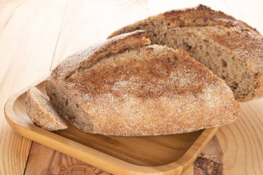 Bir tabak bambu üzerinde, bir somun ekmeğin iki taze yarısı, yakın plan, ahşap bir masanın üzerinde..