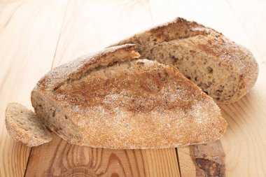 Bir somun ekmeğin iki taze yarısı, yakın plan, ahşap bir masanın üzerinde..