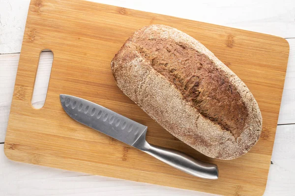 Bir somun taze pişmiş karabuğday ekmeği, metal bıçaklı, yakın plan, bambu tahtasının üzerinde..