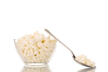 Cam bir kâse içinde mis kokulu süzme peynir, metal bir kaşık, makro, beyaz bir arka planda izole edilmiş..