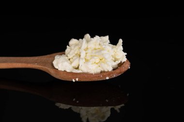 Taze, lezzetli, besleyici süzme peynir, ahşaptan yapılmış kaşık, yakın plan, siyah arka plan..