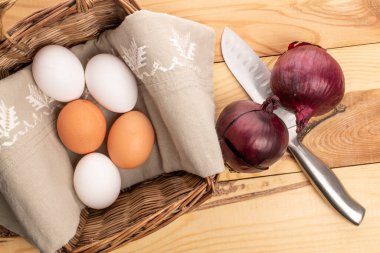 Birkaç organik diyet taze, lezzetli, beyaz ve bej, tavuk yumurtası, keten peçeteyle hasır bir sepet içinde. Yakınlarda bir metal bıçak ve ahşaptan yapılmış bir tezgahta iki ampul var..