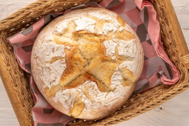 Bir somun taze kokulu buğday ekmeği ahşap bir masada sepetin içinde, makro, üst manzara.