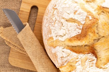 Bir somun taze kokulu beyaz buğday ekmeği ve bambu tahtasında bıçak, makro, üst manzara..