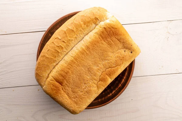 Jeden Bochník Příchutí Pšeničného Chleba Hliněném Talíři Dřevěném Stole Zblízka — Stock fotografie
