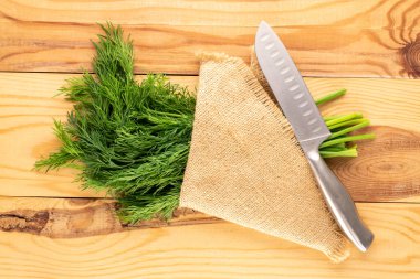Bir demet taze yeşil dereotu, bir bıçak ve tahta bir masa üzerinde jüt peçete, makro, üst manzara.
