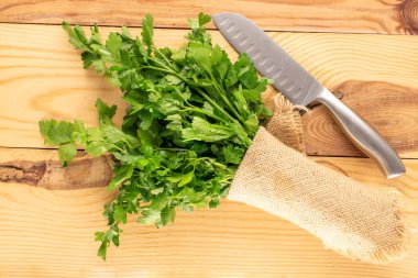 Bir demet taze maydanoz, jüt peçete ve tahta bir masada bıçak, makro, üst manzara..