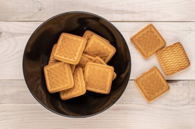 Tahta bir masada, siyah bir tabakta birkaç şekerli kurabiye, makro, üst manzara..