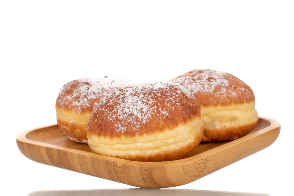 Three sweet donuts stuffed with jam on a bamboo tray, close-up, isolated on a white background.