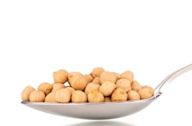 Birkaç tane pişirilmemiş humus taneciği, metal kaşık, makro, beyaz üzerine izole edilmiş..