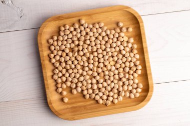 Bambu kasesinde pişmemiş organik nohut, yakın plan, beyaz ahşap masa, üst görüş..