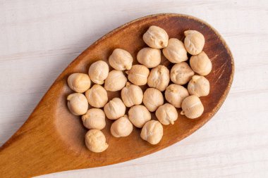 Tahta kaşıkta organik nohutlar, yakın plan, beyaz ahşap masa, üst görüş..