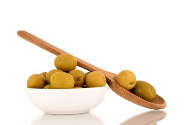 Seramik bir tabakta birkaç yeşil çukur zeytin ve beyaz üzerinde izole edilmiş bir tahta kaşık, makro..