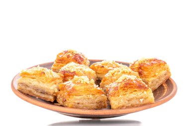 Tatlı baklava klasiği, beyaz bir arka planda izole edilmiş, makro bir kil tabakta..