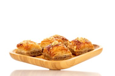Bambu tepsisindeki tatlı baklava klasiği, makro, beyaz arka planda izole edilmiş..