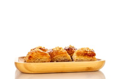 Bambu tepsisindeki tatlı baklava klasiği, makro, beyaz arka planda izole edilmiş..
