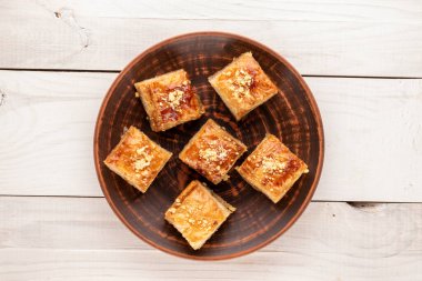 Güzel bir baklava klasiği, ahşap bir masada seramik bir tabak, makro, üst manzara..