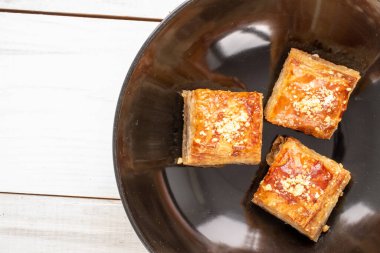 Güzel bir baklava klasiği, ahşap bir masada seramik bir tabak, makro, üst manzara..