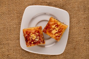 Tatlı baklava klasiği, jüt kumaş, makro, üst görünümü beyaz çay tabağı..