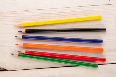 Ahşap bir masada birkaç renkli kalem, yakın plan, üst manzara..