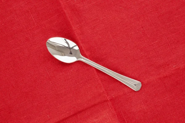 One Metal Spoon Red Linen Napkin Macro Top View — стоковое фото