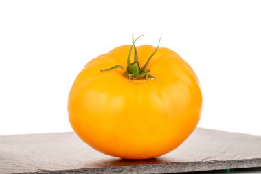 Tahta taşın üzerinde olgun sarı bir domates, yakın plan, beyaz arka planda izole edilmiş..
