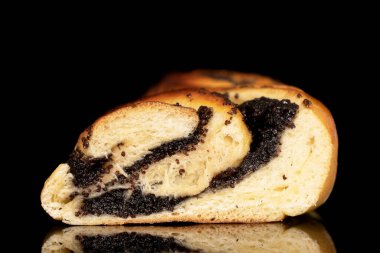 Bir bölümde haşhaş tohumlu bir çörek, yakın plan, siyah arka planda izole edilmiş..