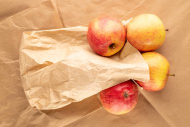 Kağıt üzerinde kağıt torbalı birkaç kırmızı organik elma, yakın plan, üst görüş..