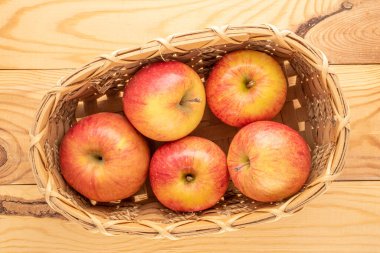 Tahta masadaki sepetin içinde birkaç kırmızı organik elma, yakın plan, üst manzara..