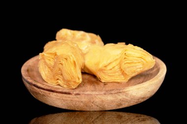 Tahta tepside üç dilim bal baklavası, yakın plan, siyah arka planda izole edilmiş..