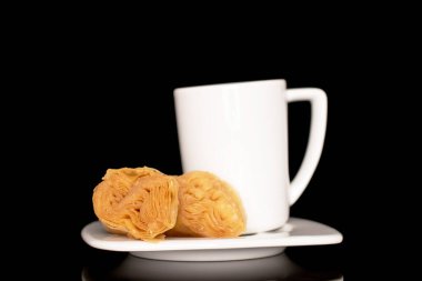 İki parça bal baklavası beyaz bir fincan üzerinde, yakın plan, siyah bir arkaplanda izole edilmiş..