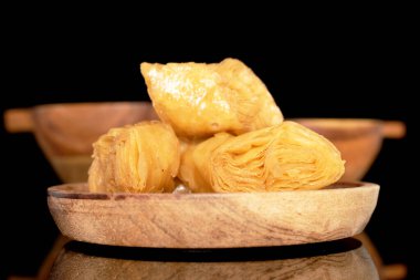 Tahta tepside üç dilim bal baklavası, yakın plan, siyah arka planda izole edilmiş..