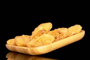 Tahta tepside birkaç dilim bal baklavası, yakın plan, siyah arka planda izole edilmiş..