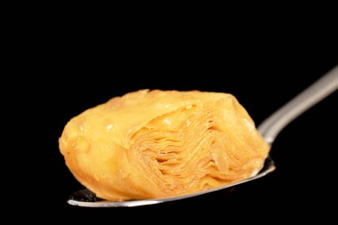 Bir parça bal baklavası, metal kaşıkla, yakın plan, siyah arka planda izole edilmiş..