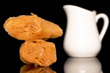 İki parça bal baklavası, beyaz süt sürahisi, yakın plan, siyah arka planda izole edilmiş..