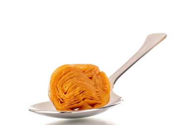 Metal kaşıkla bir dilim bal baklavası, yakın plan, beyaz arka planda izole edilmiş..