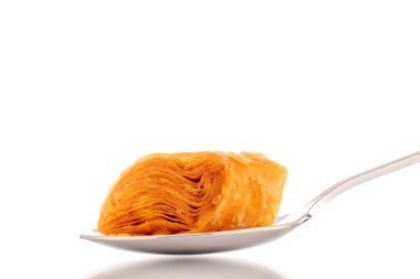 Metal kaşıkla bir dilim bal baklavası, yakın plan, beyaz arka planda izole edilmiş..