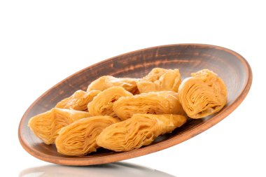 Beyaz bir zemin üzerine izole edilmiş, makro killi bir tabakta birkaç dilim bal baklavası..