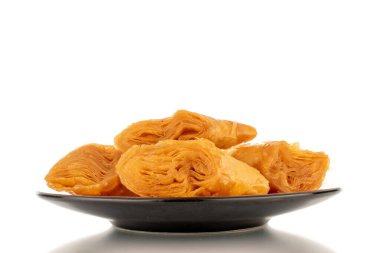 Beyaz bir arka planda izole edilmiş seramik bir fincan altlığı üzerinde birkaç dilim bal baklavası..