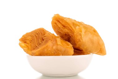 Beyaz bir arka planda izole edilmiş beyaz bir seramik fincan tabağı, makro üzerinde birkaç dilim bal baklavası..