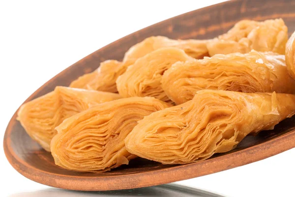 Beyaz bir zemin üzerine izole edilmiş, makro killi bir tabakta birkaç dilim bal baklavası..