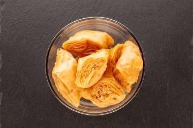 Birkaç parça bal baklavası cam bir kâse içinde kayrak taşı üzerinde, yakın plan, üst manzara..