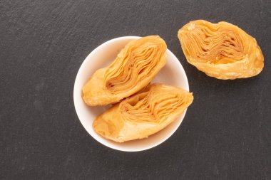 Üç parça tatlı bal baklavası, kayrak taşı üzerinde beyaz bir fincan tabağı, yakın plan, üst manzara..