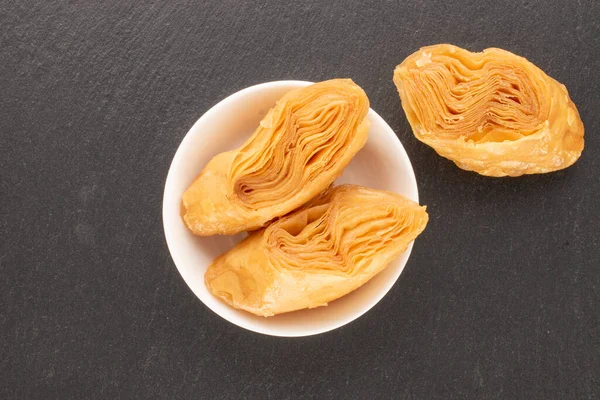 Üç parça tatlı bal baklavası, kayrak taşı üzerinde beyaz bir fincan tabağı, yakın plan, üst manzara..