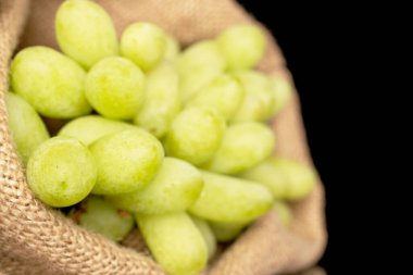 Bir demet çekirdeksiz üzüm, jüt çantalı, yakın plan, siyah arka planda izole edilmiş..