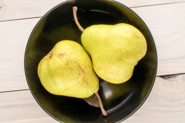 İki sulu organik armut, siyah seramik bir tabakta, ahşap bir masada, yakın plan, üst manzara..