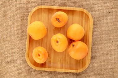 Çuval bezinde bambu tabağı olan sulu, tatlı kayısılar..