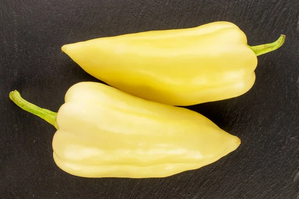 İki parlak sarı biber, kayrak taşı üzerinde, yakın plan, üst manzara..