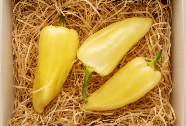Drei Leuchtend Gelbe Paprika Einer Schachtel Mit Holzspänen Nahaufnahme Draufsicht — Stockfoto