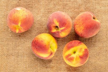 Birkaç sulu olgun şeftali jüt kumaş üzerinde, yakın çekim, üst görünüm.